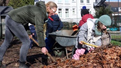 Kitaleiterin Carola Schmidt  und Kinder sammeln Laub für ein Hochbeet
