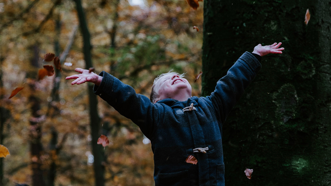 Kind wirft Herbstlauf in die Luft