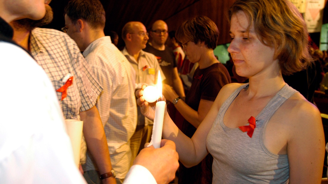 Menschen zünden im Aids Gottesdienst Kerzen an