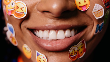 lächelnde Frau mit Emoji-Stickern im Gesicht