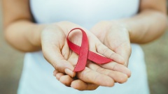 Ausgestreckte Hände mit einr roten Schleife, Symbol der Solidarität mit HIV-Positiven und Aids-Kranken.
